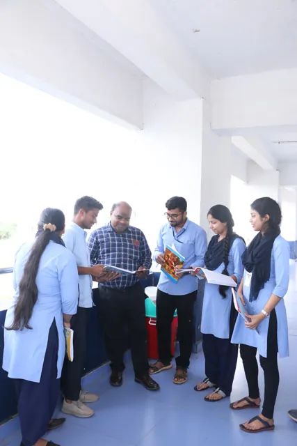 A teacher discussing notes with students in a corridor.