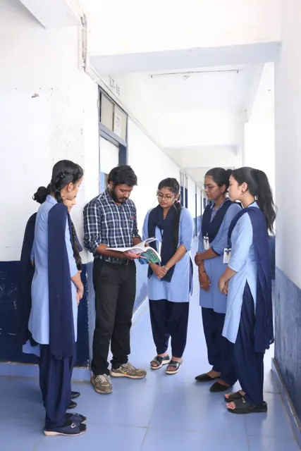 Students and a teacher talking in a college corridor.