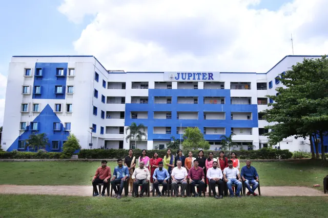 A group seated for a photo on the lawn in front of the Jupiter college building.