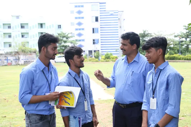 A teacher talking with three students on the campus lawn.