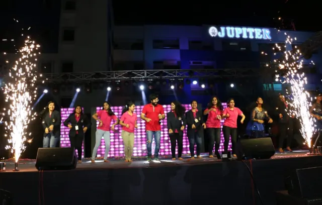 Performers on an illuminated stage with fireworks at the Jupiter Group’s 20-year celebration.