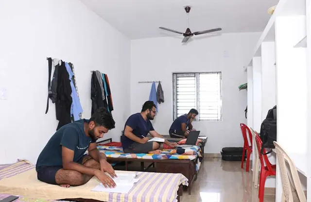 Students studying on their beds in a boys’ hostel room.