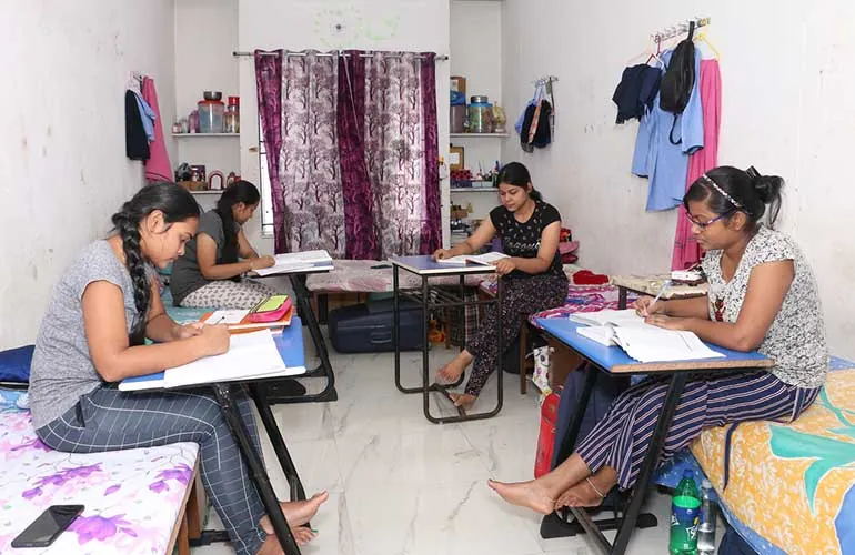 Students studying at their desks in a girls’ hostel room.