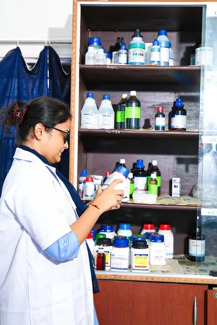 A student taking a reagent bottle from the chemistry lab shelf.