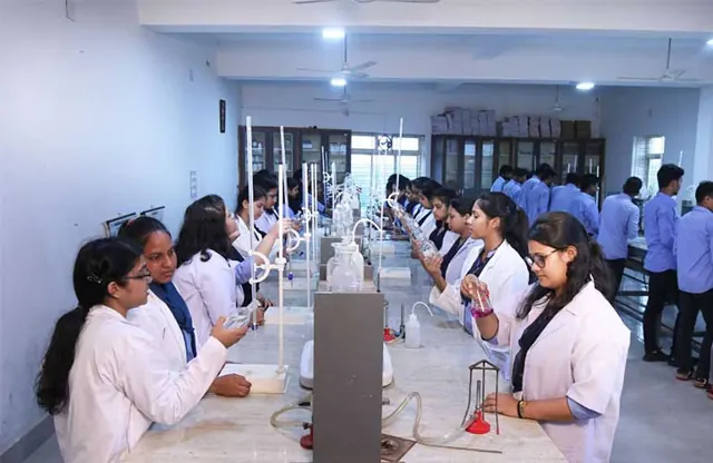 Students in lab coats working at the benches of the chemistry laboratory.