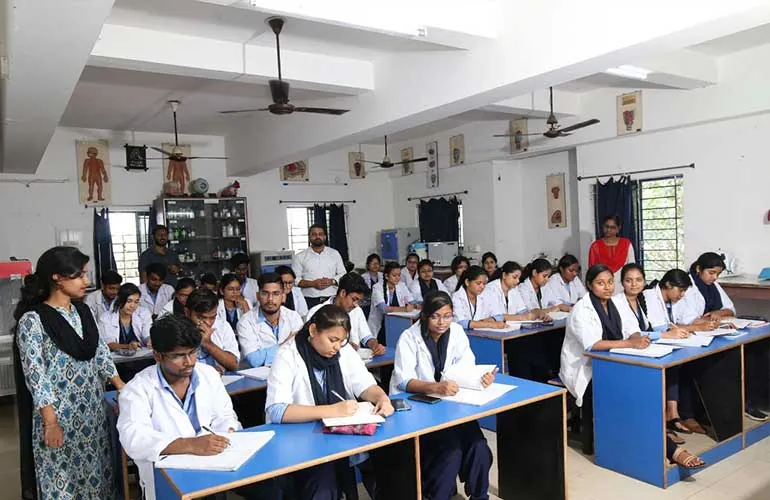 A practical class in progress, with students at lab benches and a teacher at the front.