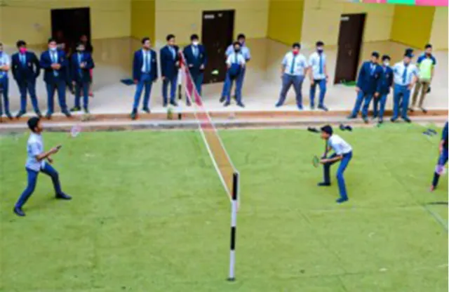 Students playing a game on the campus court while others watch.